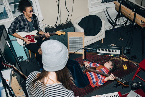 Blick von oben auf männliche und weibliche Freunde, die Gitarre spielen, während sie im Studio proben - MASF00985