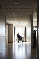 Side view of senior male patient sitting in wheelchair at hospital corridor - MASF01006