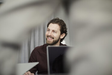 Smiling businessman sitting in front of colleague at creative office - MASF01023