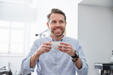 Lächelnder Geschäftsmann, der eine Kaffeetasse hält, während er im Kreativbüro steht - MASF01030