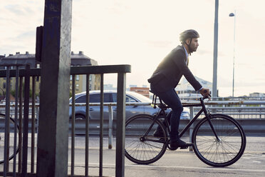 Side view of businessman cycling on street against sky - MASF01058