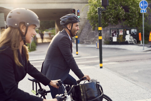 Seitenansicht eines lächelnden Geschäftspartners beim Radfahren in der Stadt - MASF01062