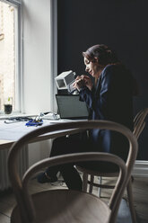 Side view of female engineer working on portable hard drive at home office - MASF01088