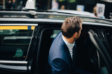 Seitenansicht eines Geschäftsmannes, der in ein Taxi in der Stadt einsteigt - MASF01103