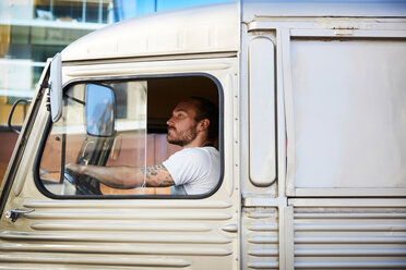 Seitenansicht eines jungen männlichen Besitzers, der einen Imbisswagen in der Stadt fährt - MASF01112