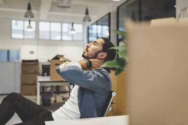 Seitenansicht eines jungen Geschäftsmannes mit Nackenschmerzen beim Sitzen in einem neuen Büro - MASF01116