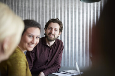 Lächelnde kreative Geschäftskollegen, die im Sitzungssaal im Büro diskutieren - MASF01134