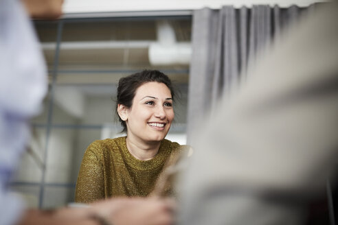 Lächelnde Geschäftsfrau sitzt mit Kollegen im Sitzungssaal während einer Sitzung - MASF01138