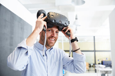 Lächelnder Geschäftsmann mit Virtual-Reality-Stimulator im Kreativbüro - MASF01149