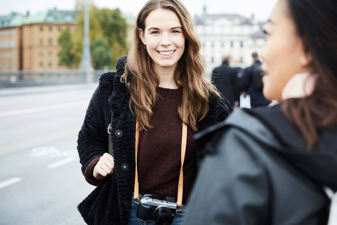 Lächelnde Frau, die mit einem Freund an einer Straße in der Stadt steht, lizenzfreies Stockfoto