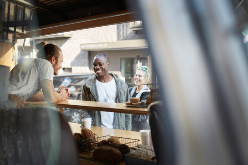Lächelnder mittelgroßer Erwachsener im Gespräch mit einem Verkäufer am Imbisswagen - MASF01248