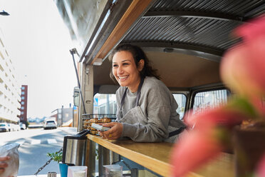 Smiling mid adult female owner at food truck in city - MASF01249
