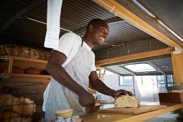 Lächelnder Verkäufer schneidet Brot, während er in einem Imbisswagen steht - MASF01253