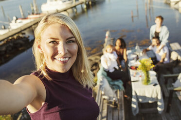Porträt einer lächelnden jungen Frau mit Freunden im Hintergrund am Bootssteg - MASF01298
