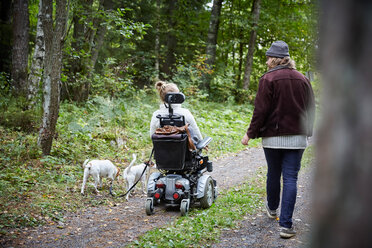 Rückansicht eines jungen Hausmeisters mit behinderter Frau und Hund im Wald - MASF01311