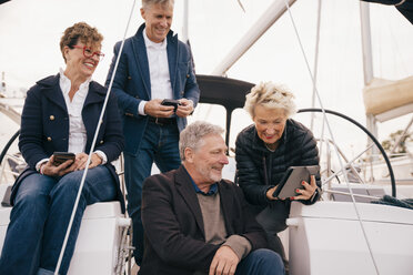 Älteres Ehepaar nutzt ein digitales Tablet, während es mit Freunden auf einer Yacht unterwegs ist - MASF01328