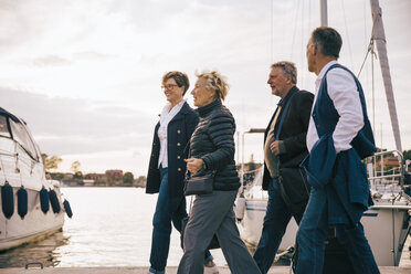 Ältere männliche und weibliche Freunde gehen auf dem Pier gegen den Himmel - MASF01329