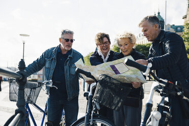 Ältere männliche und weibliche Freunde mit Fahrrädern lesen Karte in der Stadt - MASF01335