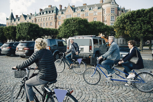 Ältere männliche und weibliche Freunde auf Fahrrädern auf der Straße in der Stadt - MASF01336