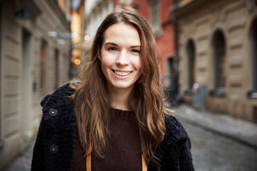 Porträt einer lächelnden jungen Frau in einer Gasse in der Stadt - MASF01350