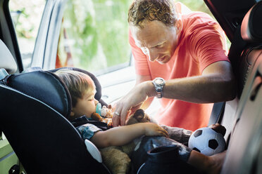 Father putting on seatbelt for son in car seat - CAVF35183