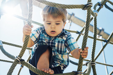 Low angle view of boy climbing ropes against sky - CAVF35188