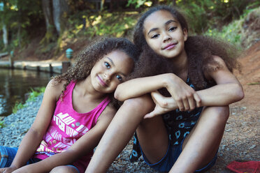 Portrait of sister sitting at lakeshore - CAVF35220