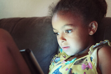 Nahaufnahme eines Mädchens, das einen Tablet-Computer benutzt, während es zu Hause auf dem Sofa sitzt - CAVF35239