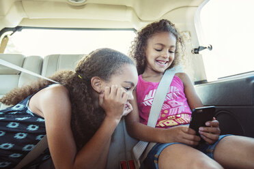 Girls looking at smart phone while traveling in car - CAVF35244
