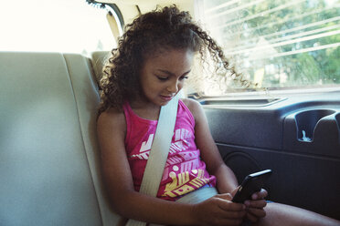 Mädchen benutzt Smartphone während der Fahrt im Auto - CAVF35245