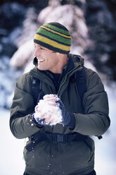 Mid-adult man making snowball - CAVF35298