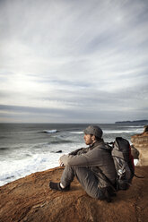 Man sitting on edge of cliff - CAVF35354