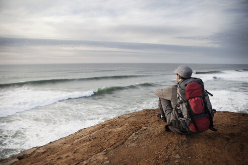 Man sitting on edge of cliff - CAVF35356