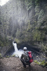 Ansicht eines Mannes mit Blick auf einen Wasserfall im Wald - CAVF35369