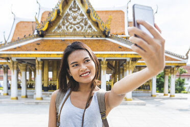 Thailand, Bangkok, portrait of smiling tourist taking selfie with smartphone - WPEF00182