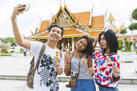 Thailand, Bangkok, drei Freunde mit Straßenessen machen ein Selfie, lizenzfreies Stockfoto