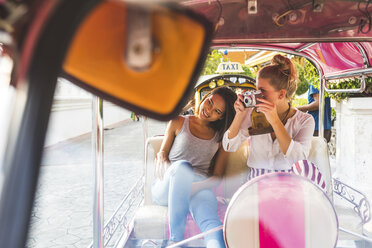 Thailand, Bangkok, two friends riding tuk tuk taking pictures with an old camera - WPEF00192