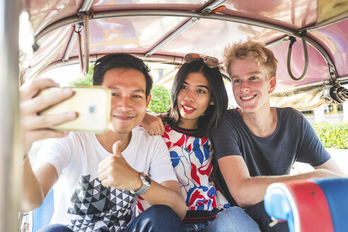 Thailand, Bangkok, drei Freunde fahren Tuk Tuk und machen Selfie mit Smartphone - WPEF00194