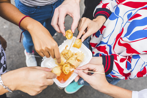 Thailand, Bangkok, Khao San Road, Gruppe von Freunden, die auf einem Straßenmarkt einheimisches Essen probieren, Nahaufnahme, lizenzfreies Stockfoto