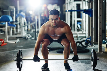 Man lifting barbell in gym - ABIF00240