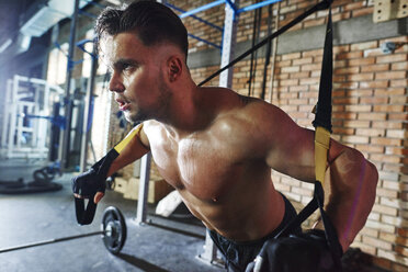 Mann bei einer Übung mit Aufhängegurten im Fitnessstudio - ABIF00242