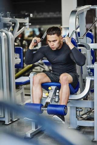 Ein Mann trainiert mit einem Trainingsgerät in einem Fitnessstudio, lizenzfreies Stockfoto
