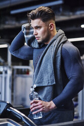 Mann mit Wasserflasche auf einem Laufband im Fitnessstudio - ABIF00253