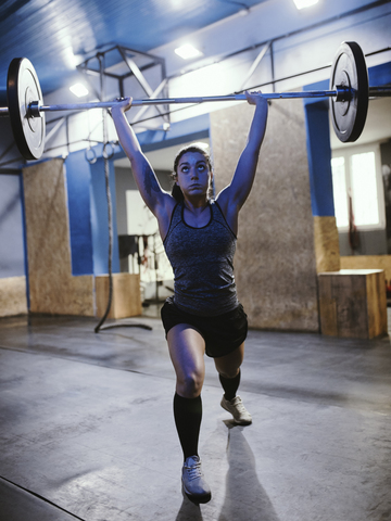 Frau hebt Langhantel im Fitnessstudio, lizenzfreies Stockfoto