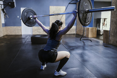 Woman lifting barbell in gym - ZEDF01266