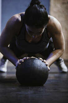 Frau macht Liegestütze auf einem Ball im Fitnessstudio - ZEDF01274