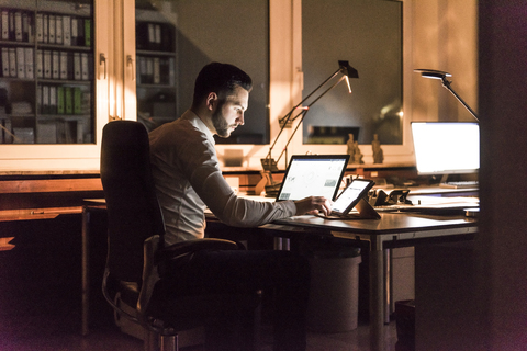 Geschäftsmann arbeitet am Schreibtisch im Büro bei Nacht, lizenzfreies Stockfoto