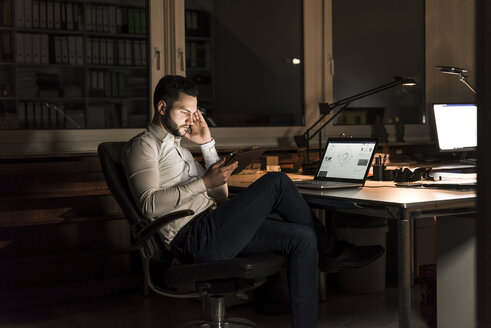 Businessman using tablet in office at night - UUF13200