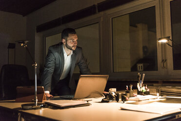Businessman working in office at night - UUF13203