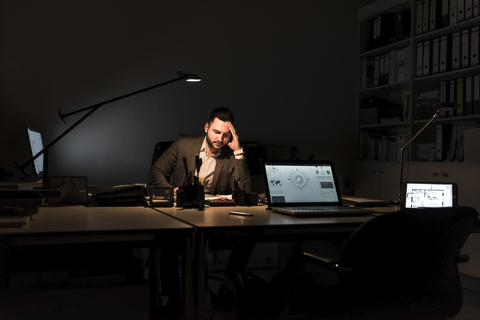 Businessman working in office at night stock photo